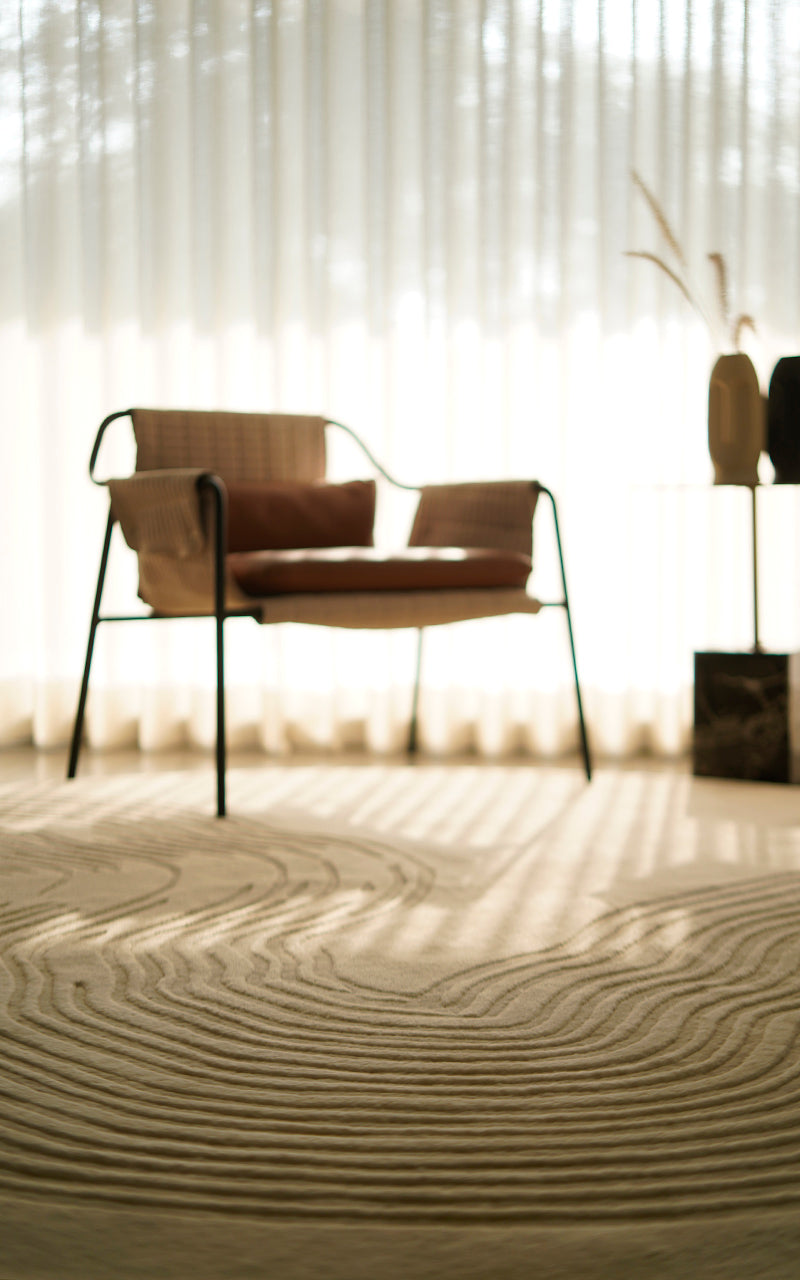 A beautiful set up of a rug with light filtering through the curtains creating a soft glow. The rug gives an effect similar to the sand by the beach
